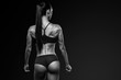 © USM Photography - Healthy fit strong young woman in sportswear standing with her back looking over her shoulder Copy space Clipping path Rear view Muscular female back, booty, buttocks Black and white close-up shot