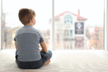 Lonely Little Boy Sitting On Floor In Room. Autism Concept