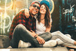 © BalanceFormCreative - Young teen couple sitting by the wall and hangout at the street .Embrace each other and laughing .
