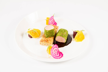 Roast pork tenderloin with crispy potato bread, marinated beetroots and green pepper sauce on a plate on a white background