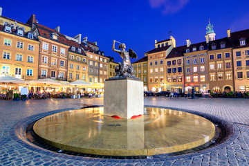 Night view of the bronze statue of Mermaid on the Old Town Market Square of Warsaw, surrounded by colorful old houses, Poland.