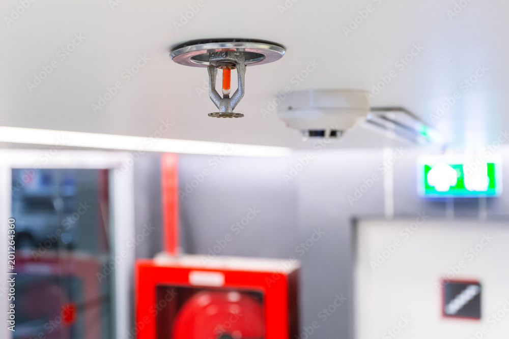 Fire Sprinkler, focus at selective, Fireplace in the office for safety and to reduce damage in case of fire, signage exit blur background. - obrazy, fototapety, plakaty 