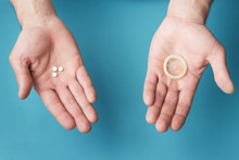 Male Contraceptives. Pills And Condom In The Hands Of Men