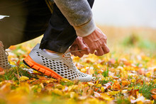 Closeup Of Man Tying Shoelaces On Autumn Grass In Park