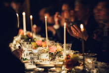 People Enjoy A Family Dinner With Candles. Big Table Served With Food And Beverages.