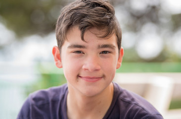 close up portrait of a young teenager man looking at camera with a joyful smiling expression, agains