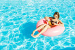 © sosiukin - Beautiful happy woman reading a book with inflatable ring relaxing in blue swimming pool