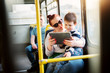 © dusanpetkovic1 - Mature lady is holding her little toddler in her lap and showing tablet videos to him while traveling with bus.