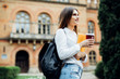 © F8  \ Suport Ukraine - Smiling young student girl holding coffee cup, outdoors with notebooks, having rest in university campus. Education concept, copy space