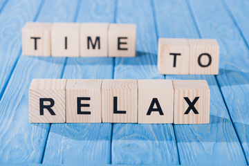 Wall Mural - close up view of arranged wooden blocks into time to relax phrase on blue wooden surface