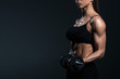 © LIGHTFIELD STUDIOS - cropped view of female bodybuilder training with dumbbells, isolated on grey