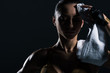 © LIGHTFIELD STUDIOS - sweaty tired bodybuilder with towel after training, isolated on black