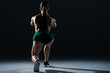 © LIGHTFIELD STUDIOS - back view of muscular sportswoman doing lunges, on black