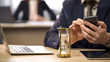 © motortion - Hourglass measuring time, businessman using mobile phone, procrastination