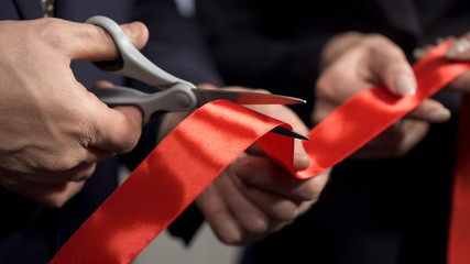 business people hands cutting red ribbon close-up, new project, opening ceremony