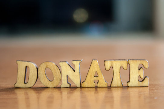 The word 'donate' made of wooden letters. wood inscription on table