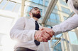 © salomonus_ - Handshake of two young men against a multi-storey office building. Make a deal. Friendly relations. Office staff. Signing of the contract