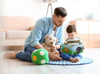 Wall Mural - Dad and his son reading book at home