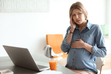 Canvas Print - Pregnant woman suffering from headache at workplace