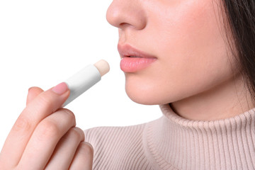 Wall Mural - Young woman applying cold sore balm on lips against white background, closeup