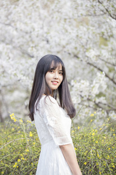 Fototapete - Beautiful girl enjoying the spring flower outdoors in the park