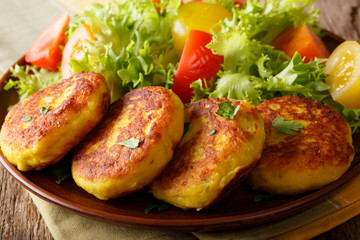 Wall Mural - Freshly prepared potato pancakes are served with fresh salad close-up. horizontal