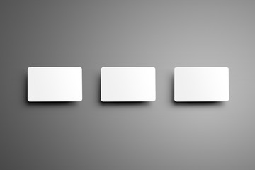 Wall Mural - Realistic white mockup of a three  bank (gift) card with shadows placed horizontally on a gray background.