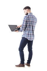Back side view of modern stylish bearded business man using laptop touch screen. Full body isolated on white background. 