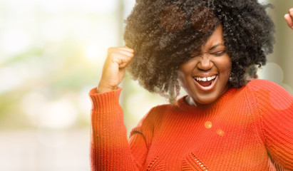 Wall Mural - Beautiful african woman happy and excited celebrating victory expressing big success, power, energy and positive emotions. Celebrates new job joyful, outdoor