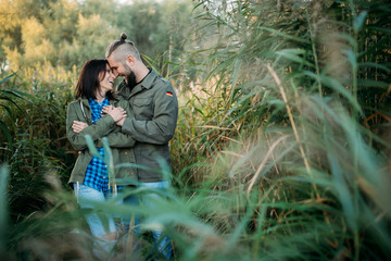 Walk a guy and a girl. Love story by the lake in the tall grass. Youth in nature.