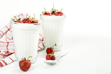 Dessert yogurt and strawberry layers in a glass on a red striped napkin on a white background