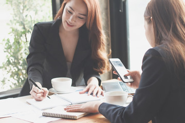 Two office workers are sitting at coffee shop,Businessmen are agreeing to work in coffee shop,Young girl is drinking coffee at coffee shop,Businessmen are talking about work on a coffee shop.