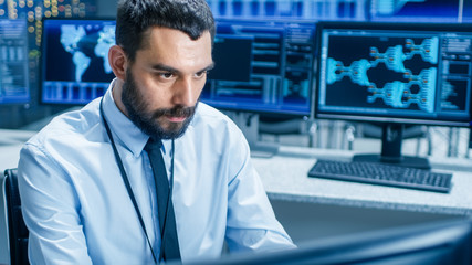 Leinwandbilder - In the System Control Center Technical Operator Monitors Displays at His Workstation. He's Surrounded by Displays Showing Relevant Data. In the Background Data with Interactive Map.