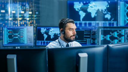 Leinwandbilder - System Control Room Dispatcher Talks into Headset. He Controls Correct Work of the Facility. In the Background Multiple Monitors Show Technical Data.