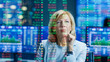 © Gorodenkoff - Stock Market Female Top Manager Looks at Projected Ticker Numbers and Graphs. Behind Her Room Full of Screens and Statistics.