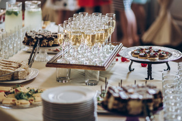 Wall Mural - stylish champagne glasses and food  appetizers on table at wedding reception. luxury catering at celebrations. serving food and drinks at events concept