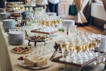 stylish champagne glasses and food appetizers on table at wedding reception. luxury catering at cele