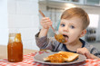 © New Africa - Little boy eating jam at table in kitchen