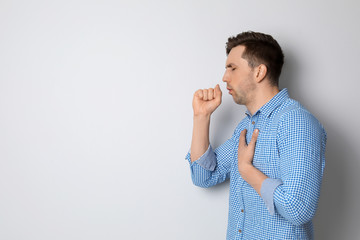 Wall Mural - Young man coughing on light background