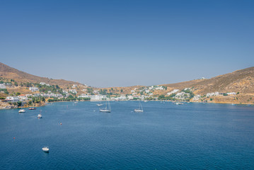 Beautiful sunny holiday coast view to a empty holiday bay with crystal clear blue water sandy greek beach for sunbathing and some boats cruising fishing, Patmos Island, Kos, Dodecanese/ Greece