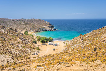 Beautiful sunny coast view to the greek beach Psili Ammos and blue aegean sea with crystal clear water sandy beach with some boats fishing cruising small hills covering, Patmos, Dodecanese, Greece 