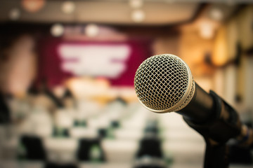 microphone on abstract blurred of speech in seminar room or speaking conference hall light, speaker 