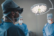© supamotion - Surgeon using augmented reality holographic hololens glasses while operating in modern operation theater