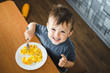 © komokvm - a child in a t-shirt in the kitchen eating an omelet, a fork