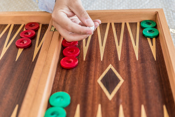 Playing backgammon on a wooden board with dices