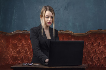 Businesswoman, happy woman in suit using laptop for work in vintage interior