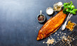 © jarvna - Smoked whitefish with salt and pepper in dish, fork and knife, lemon, basil, tomatoes, little cucumbers, parslay, grid for grilling, cherry wood chunks  on a black background, top view, overhead, flat