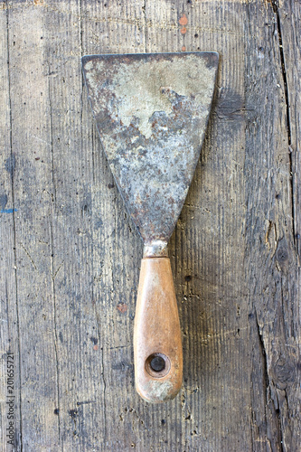 Fotografía Old, dirty putty knife against wooden plank. Tool series.