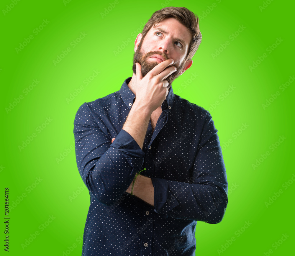 Young hipster man with big beard thinking and looking up expressing ...