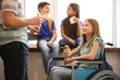 © Africa Studio - Teenage girl in wheelchair with classmates eating sandwiches at school